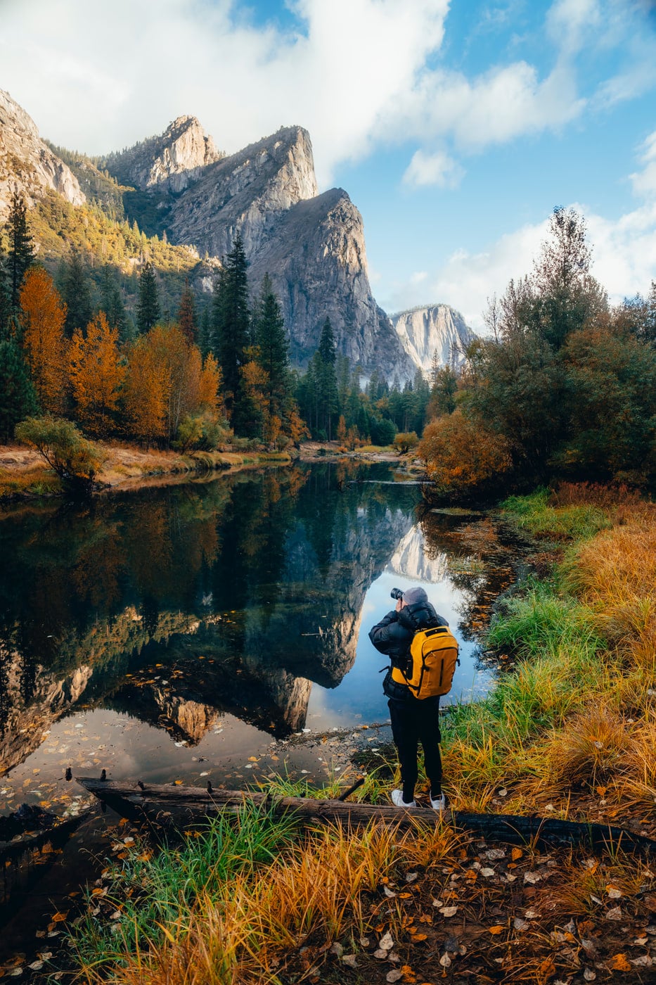 Max with a yellow pack photographing the Merced River in fall Yosemite