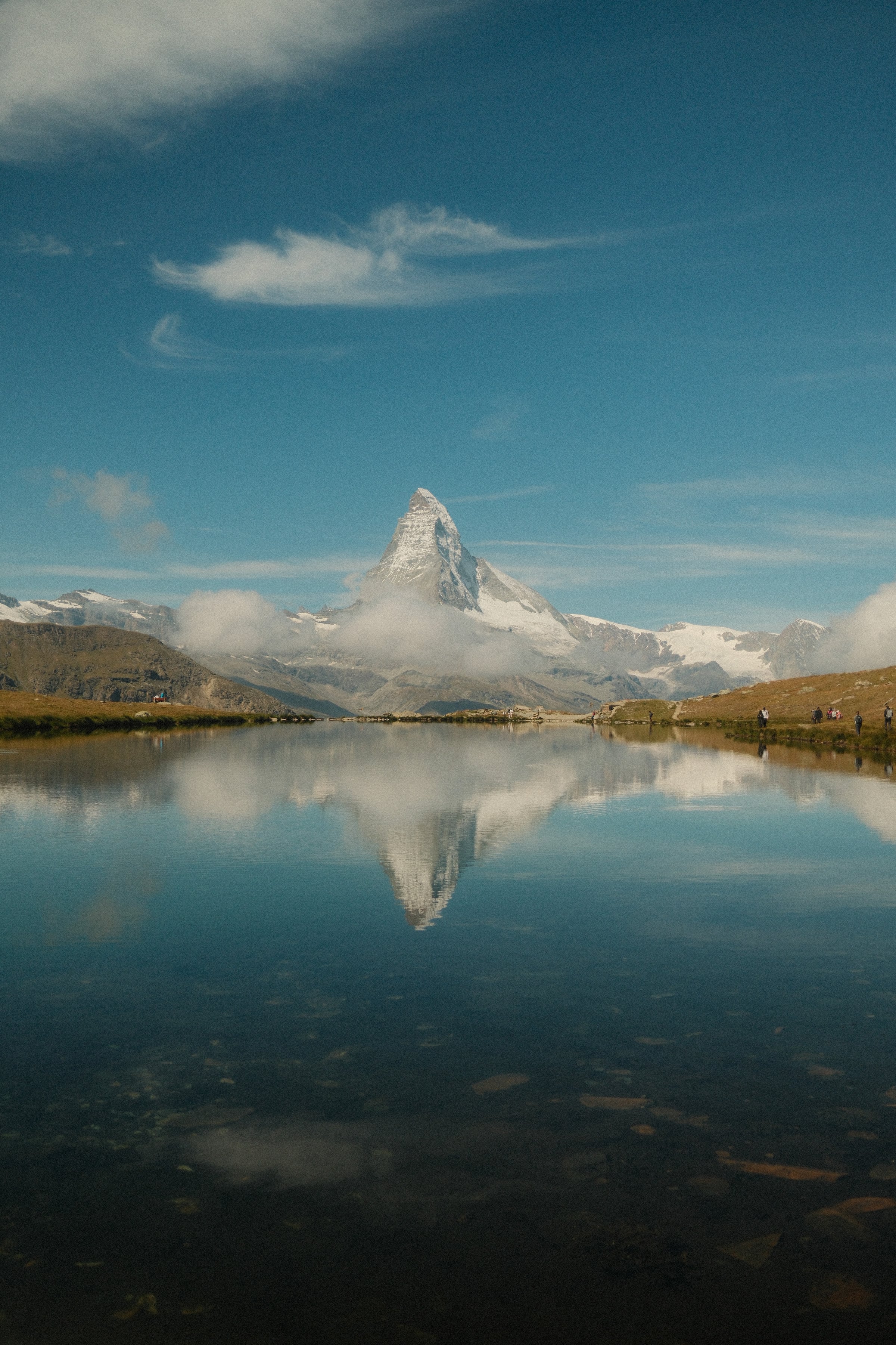 The Matterhorn mirrored in a still alpine lake under a blue sky
