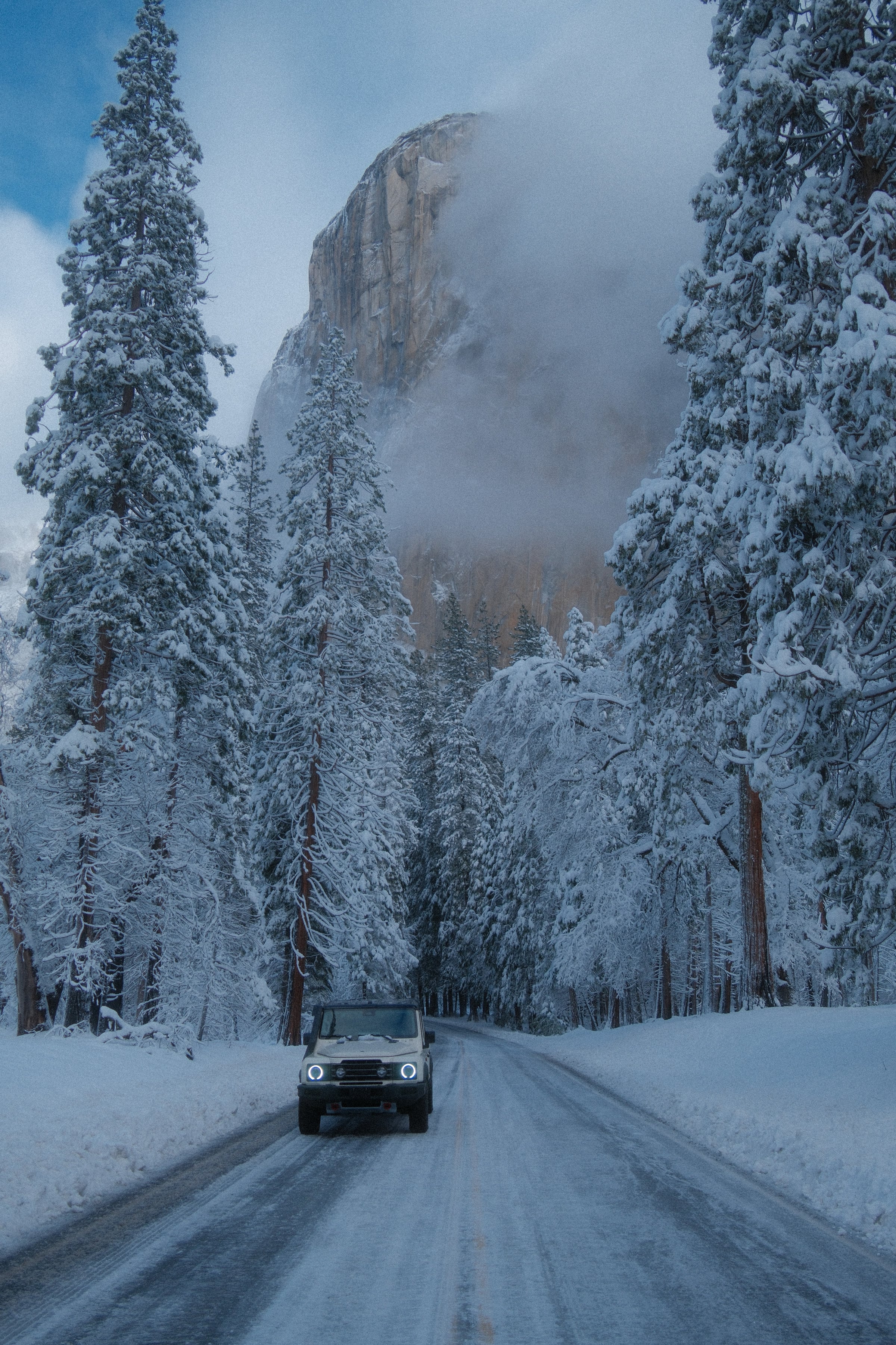 A vehicle on a snowy road below El Capitan in winter Yosemite