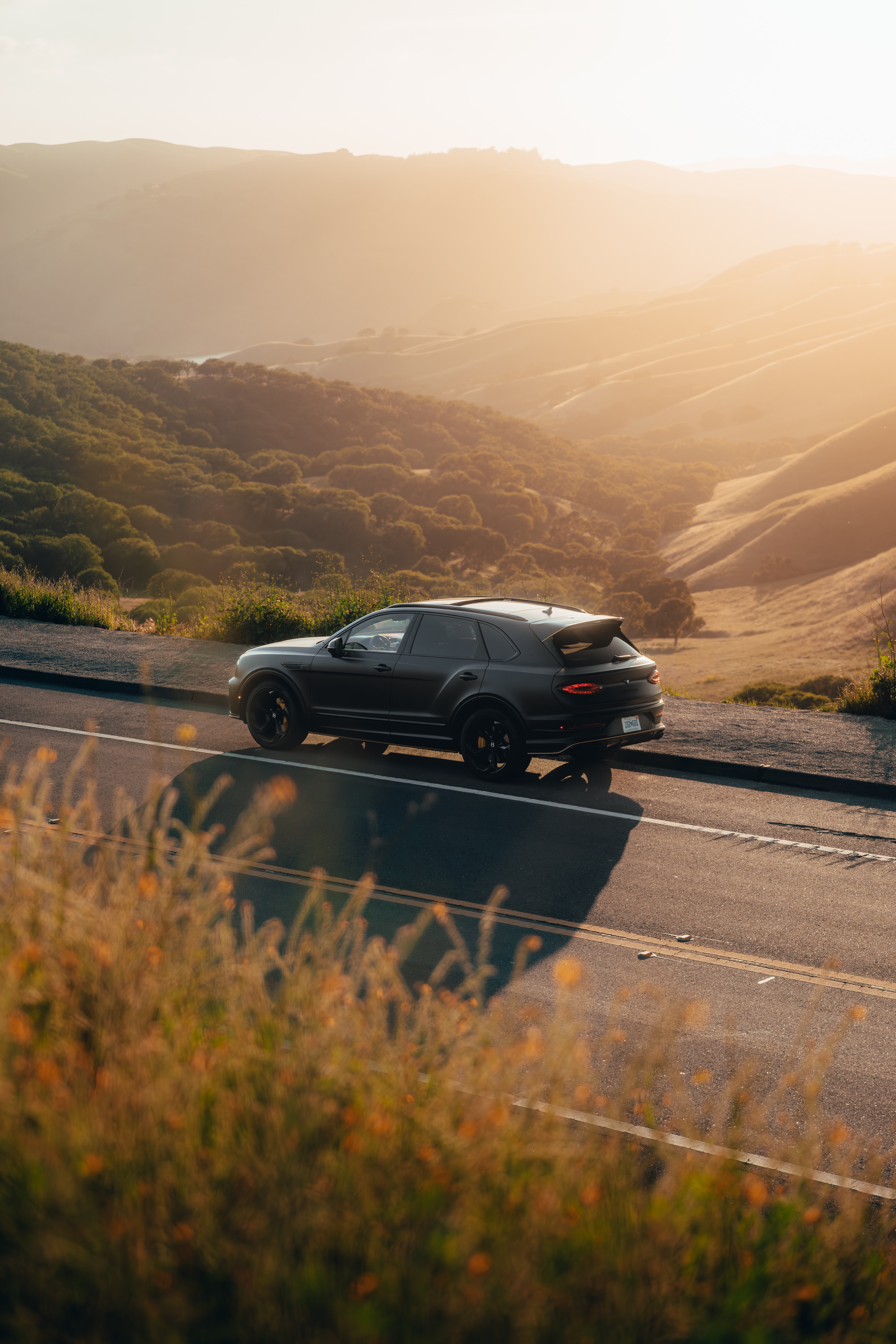 Bentayga driving on a golden-hour California hillside road