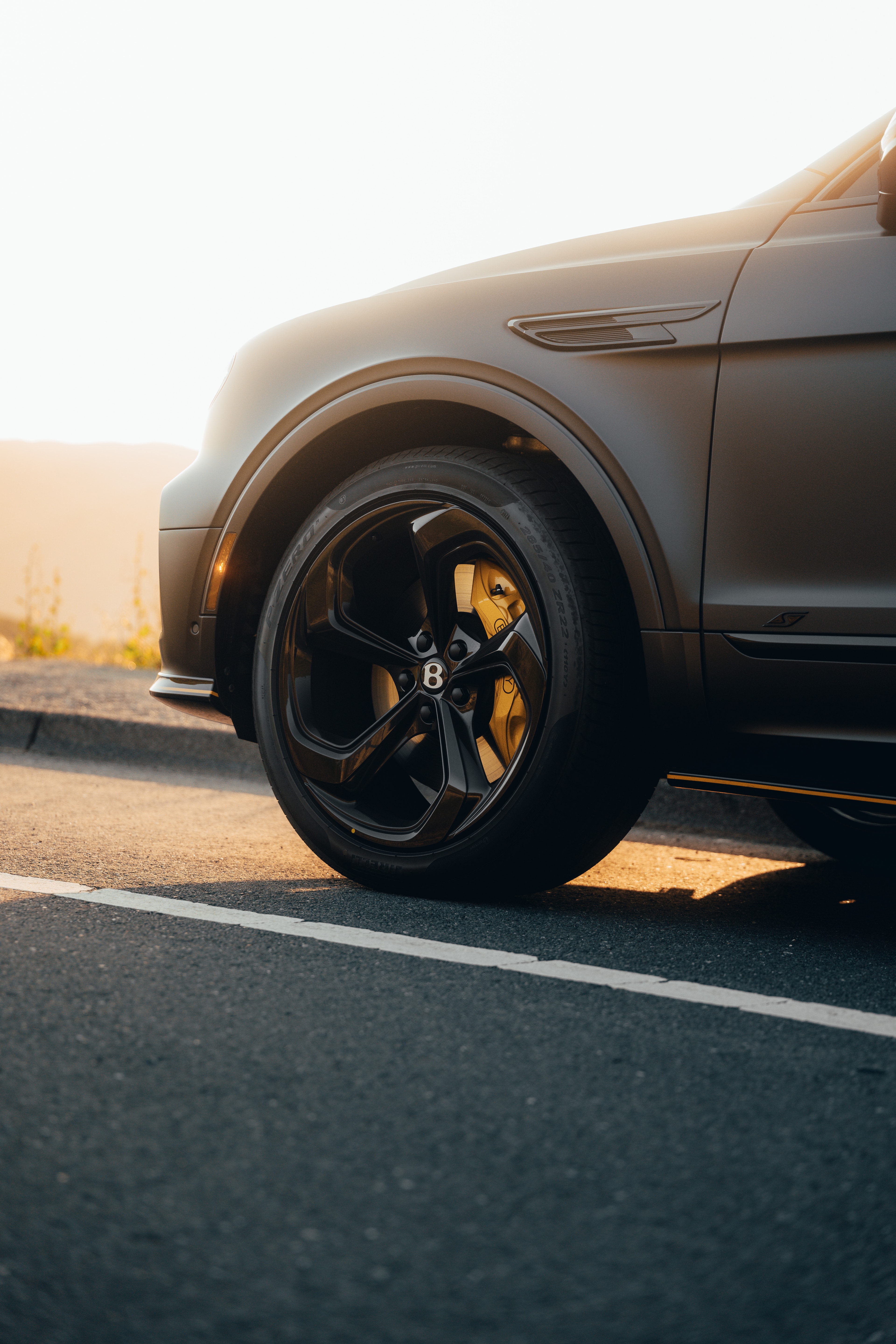 Bentayga front wheel — yellow brake caliper at golden hour