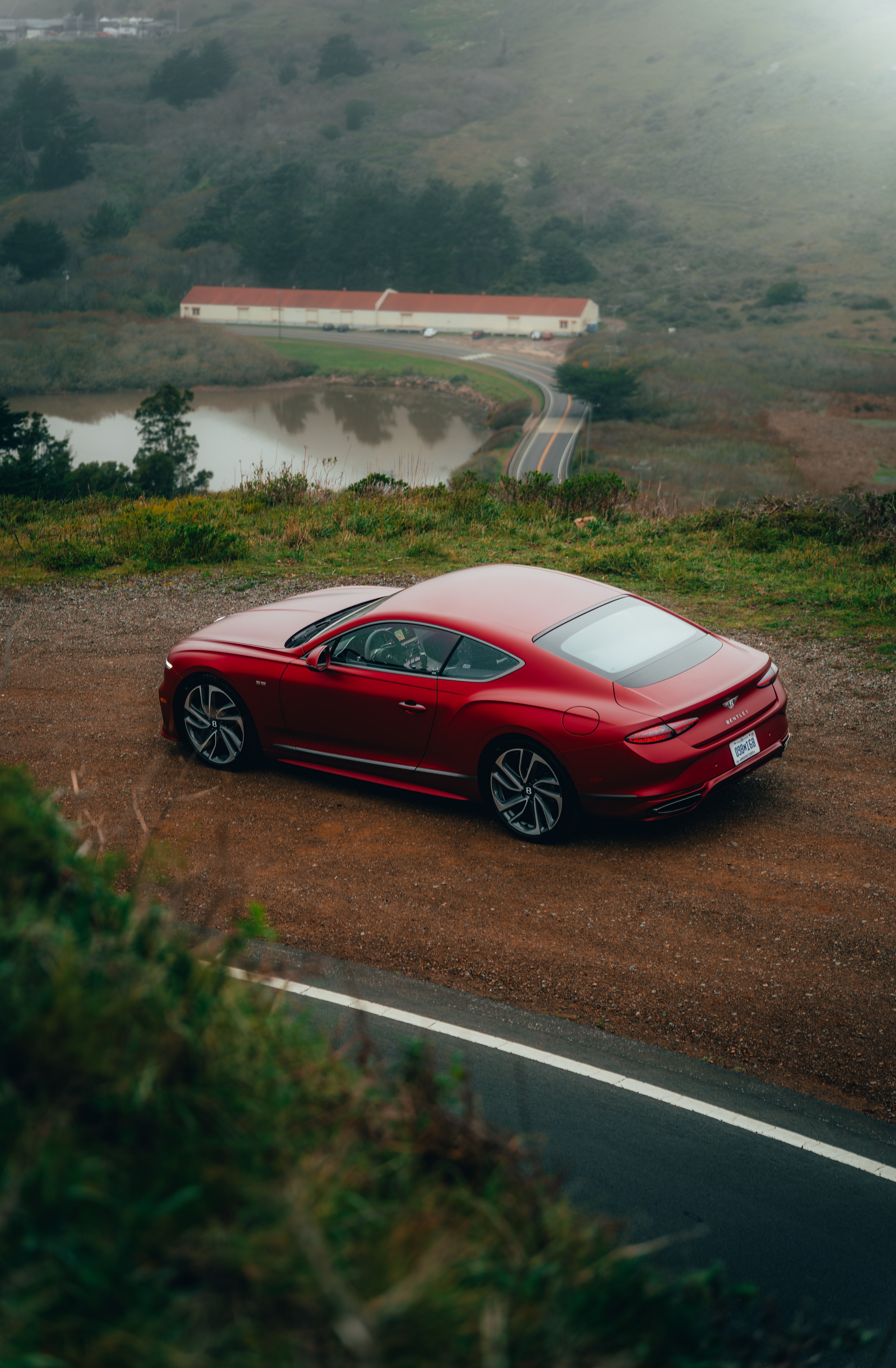 Aerial — Continental GT at a coastal overlook with pond and farmhouse