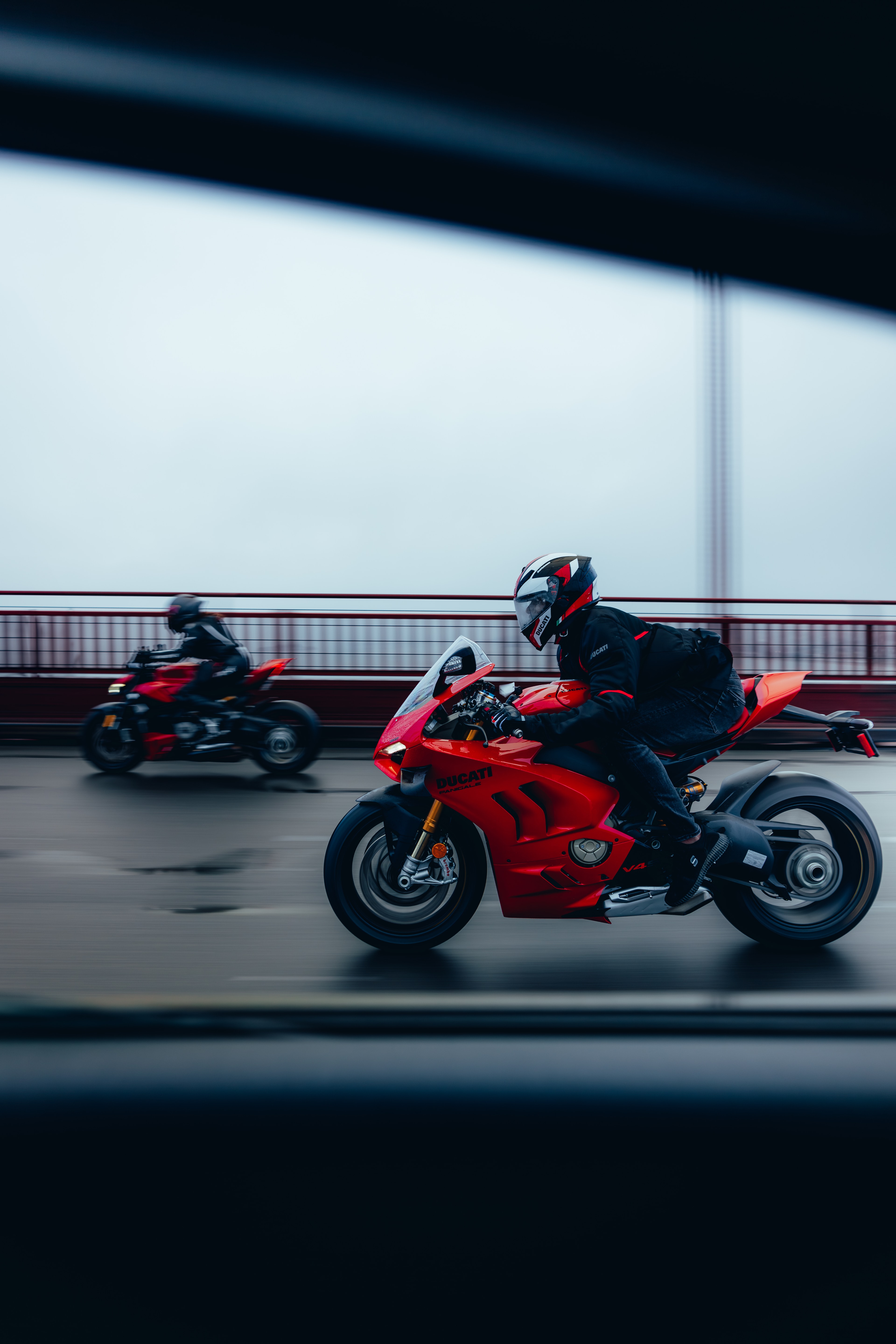Two Ducati Panigale V4S motorcycles crossing the Golden Gate Bridge in fog, shot from a chase car