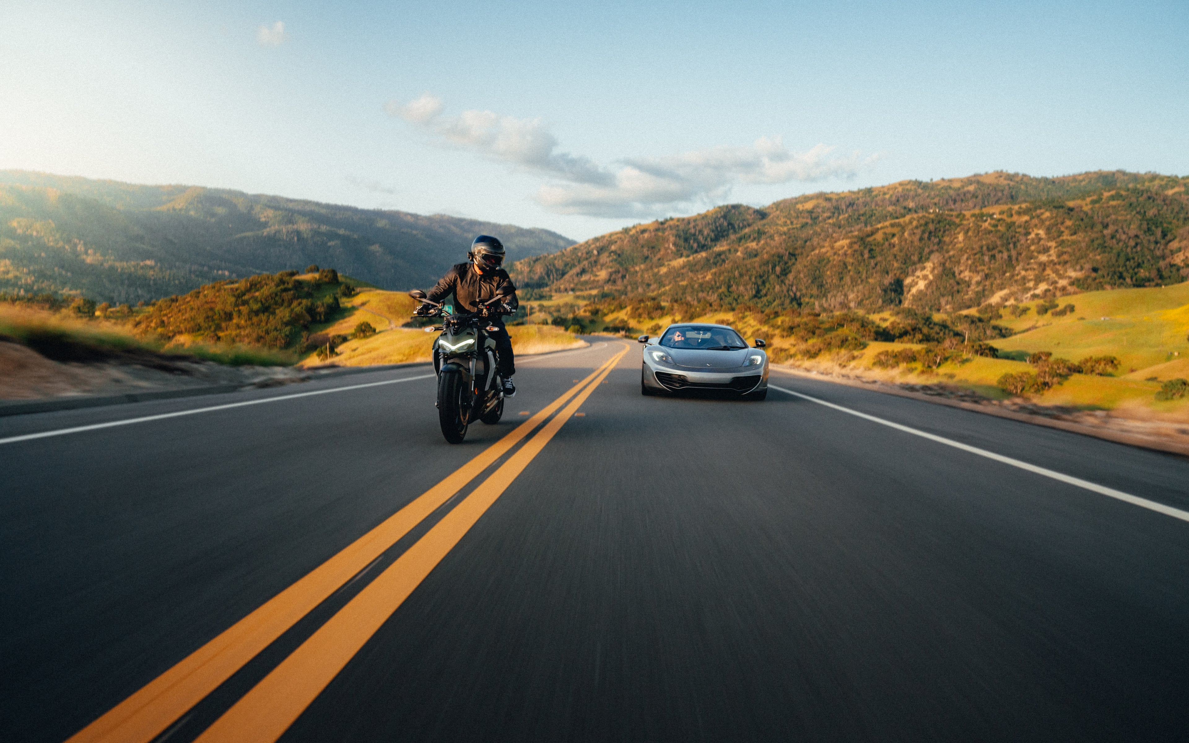Ducati Street Fighter rider alongside a silver McLaren on a golden-hour Bay Area road