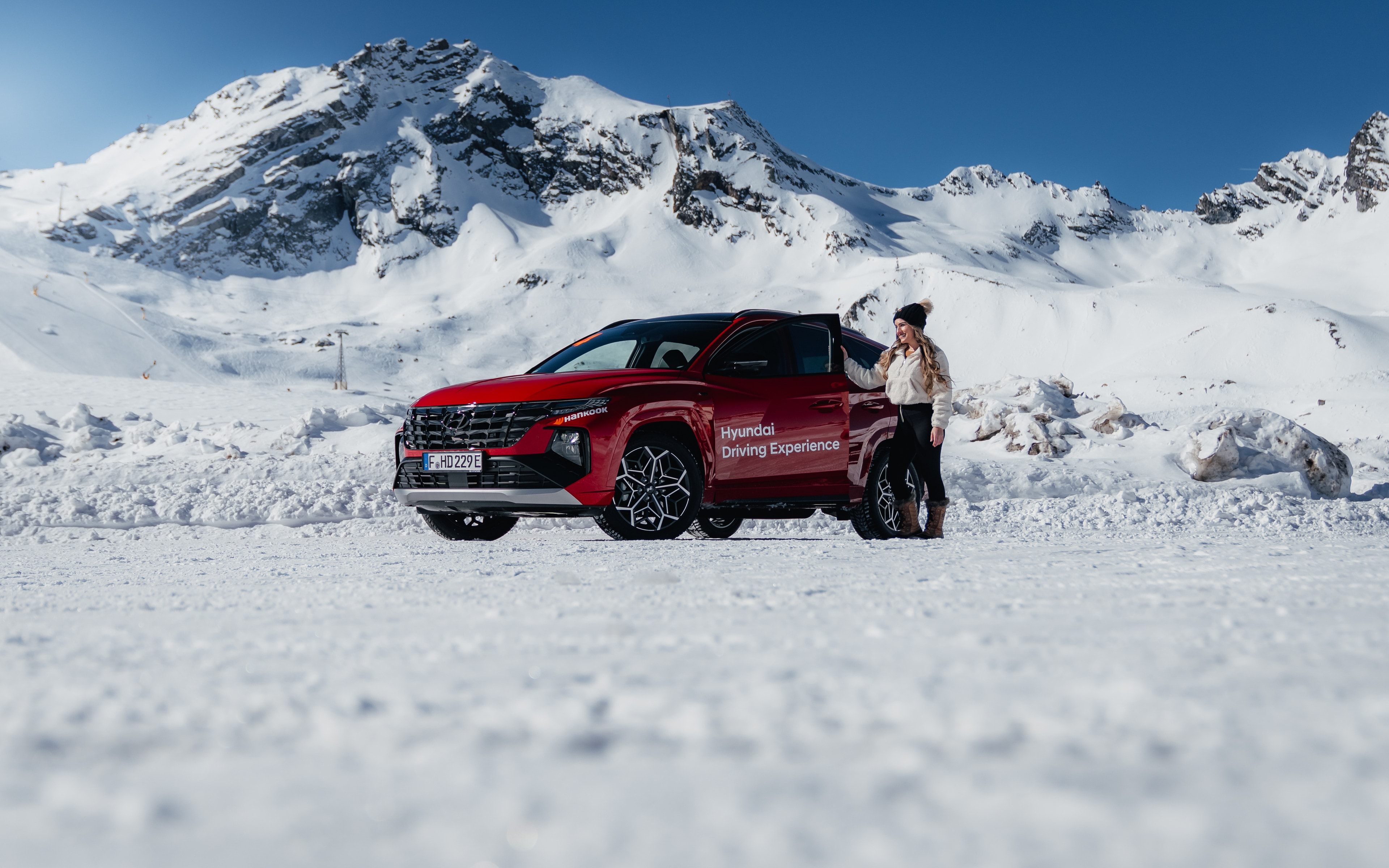 Red Hyundai Tucson on the glacier at the Hyundai Driving Experience, snowy alpine peaks behind