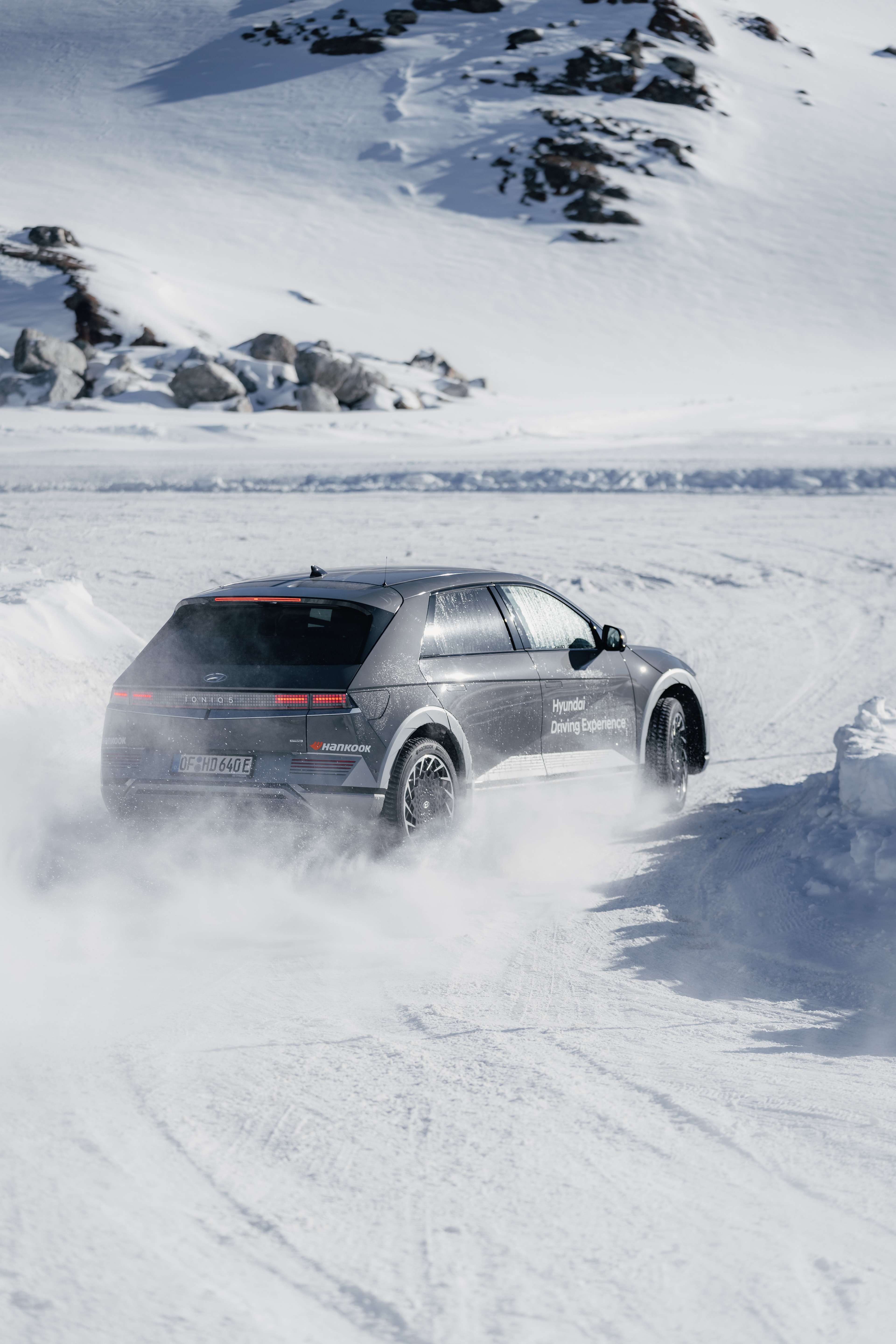 Hyundai IONIQ 5 drifting on the glacier, rear three-quarter, distant peaks