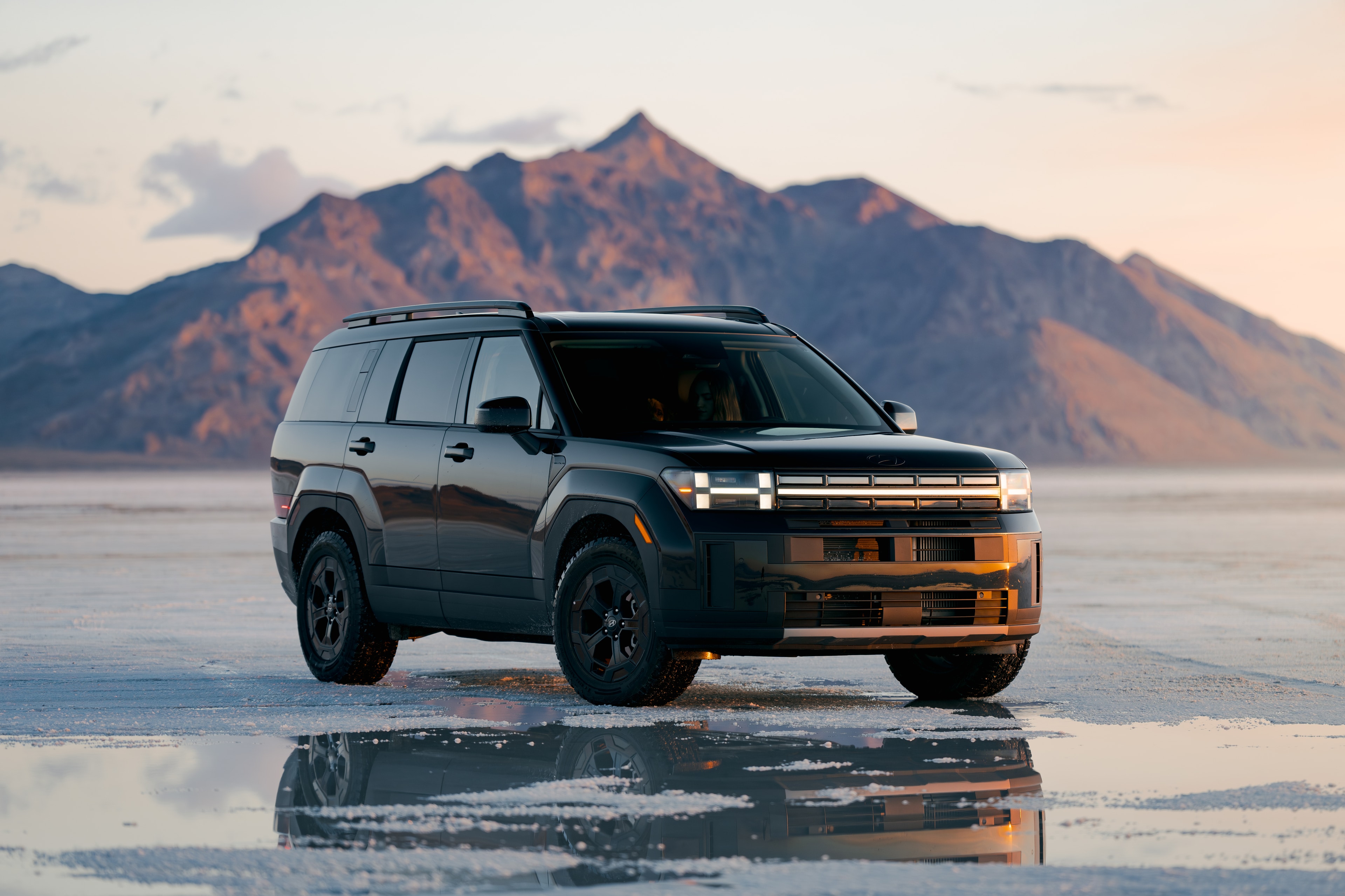 Hyundai Santa Fe front three-quarter on the Bonneville salt flats, mountains reflected in the water