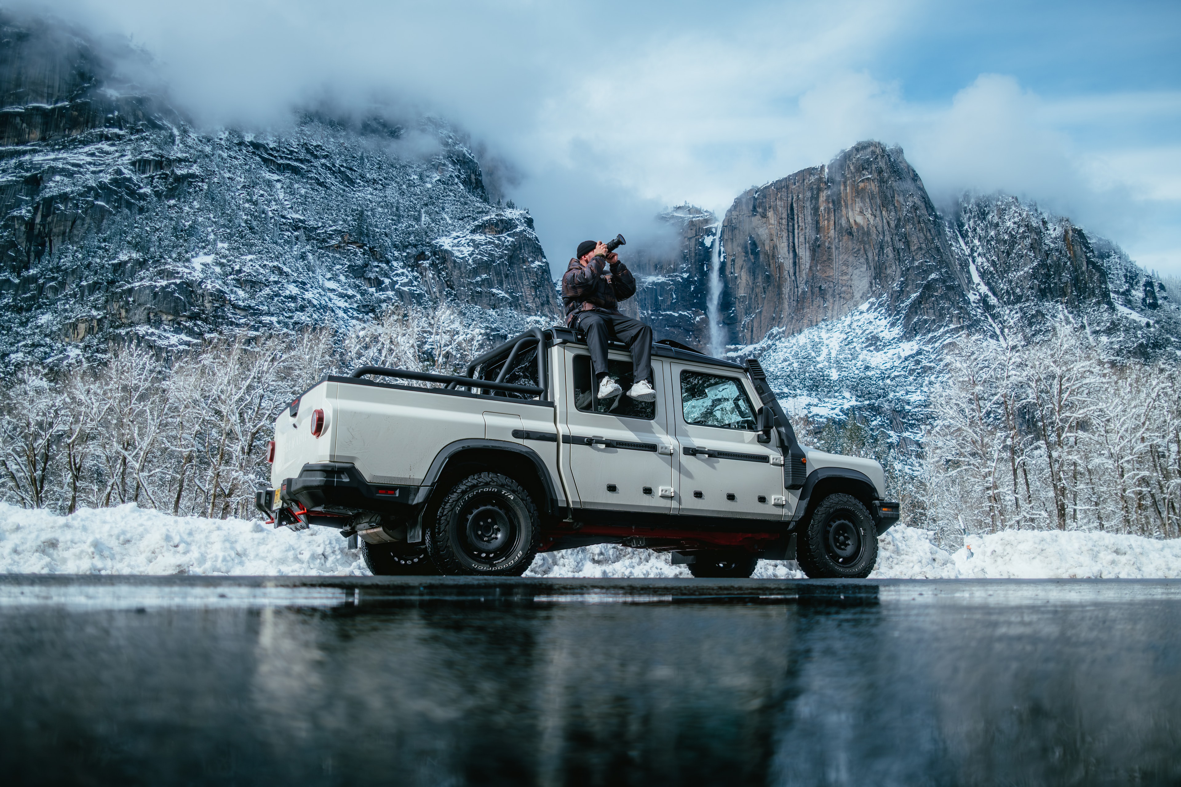 INEOS Grenadier Quartermaster beside a frozen lake reflecting Yosemite Falls, a photographer shooting from the roof