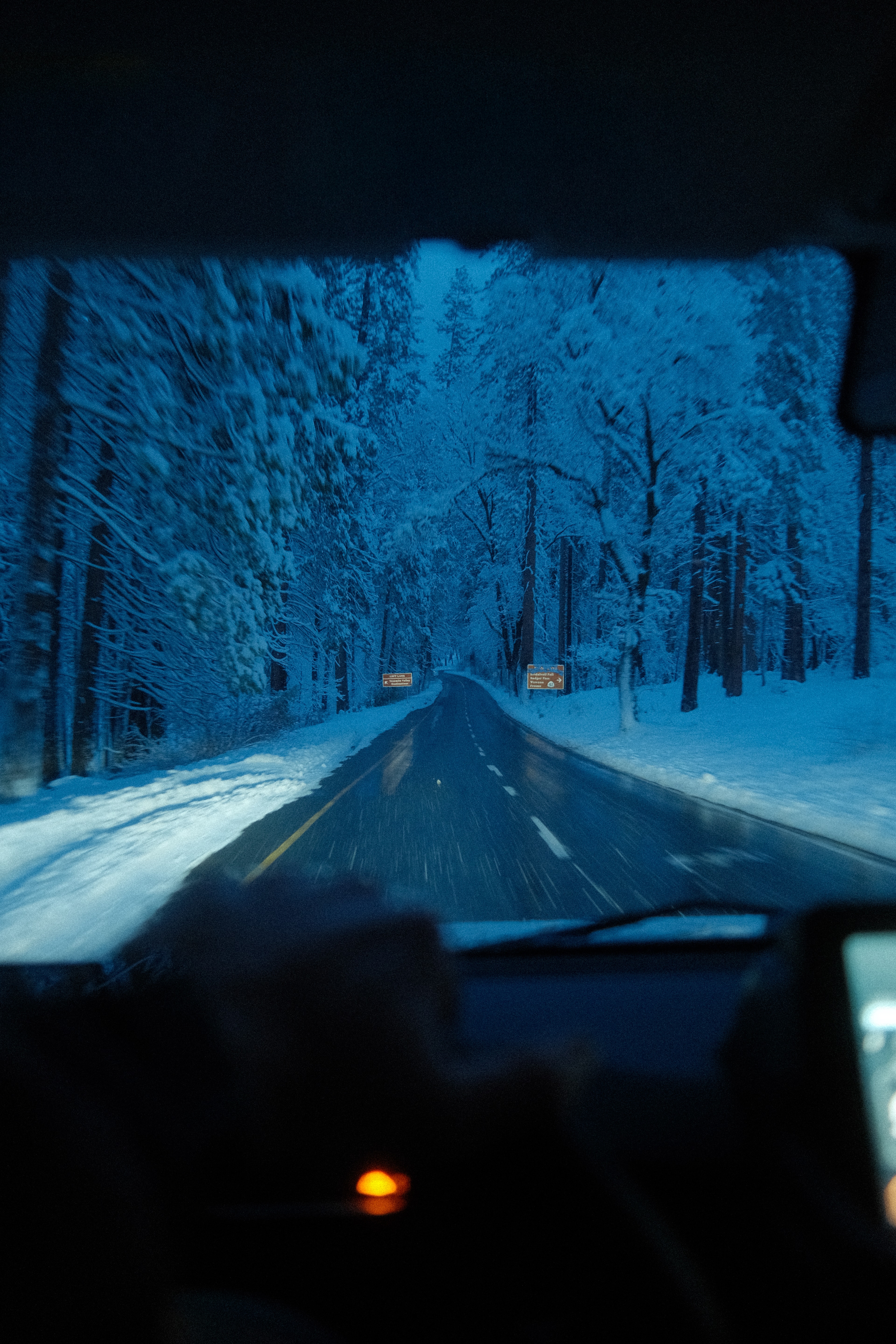 In-cab view of a night drive through the snowy forest, headlights on the road