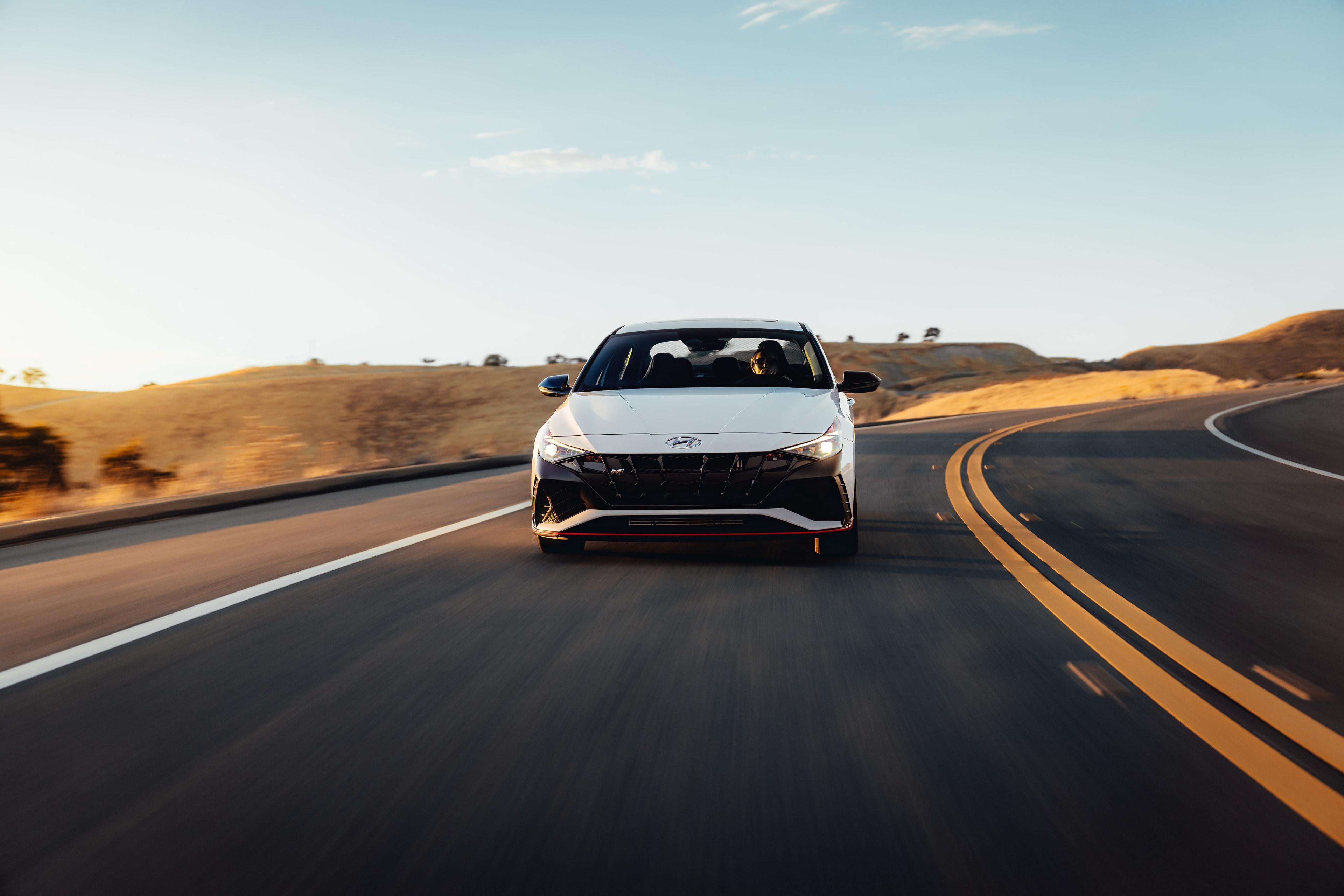 Hyundai Elantra N head-on in motion on a golden-hour California ridge road