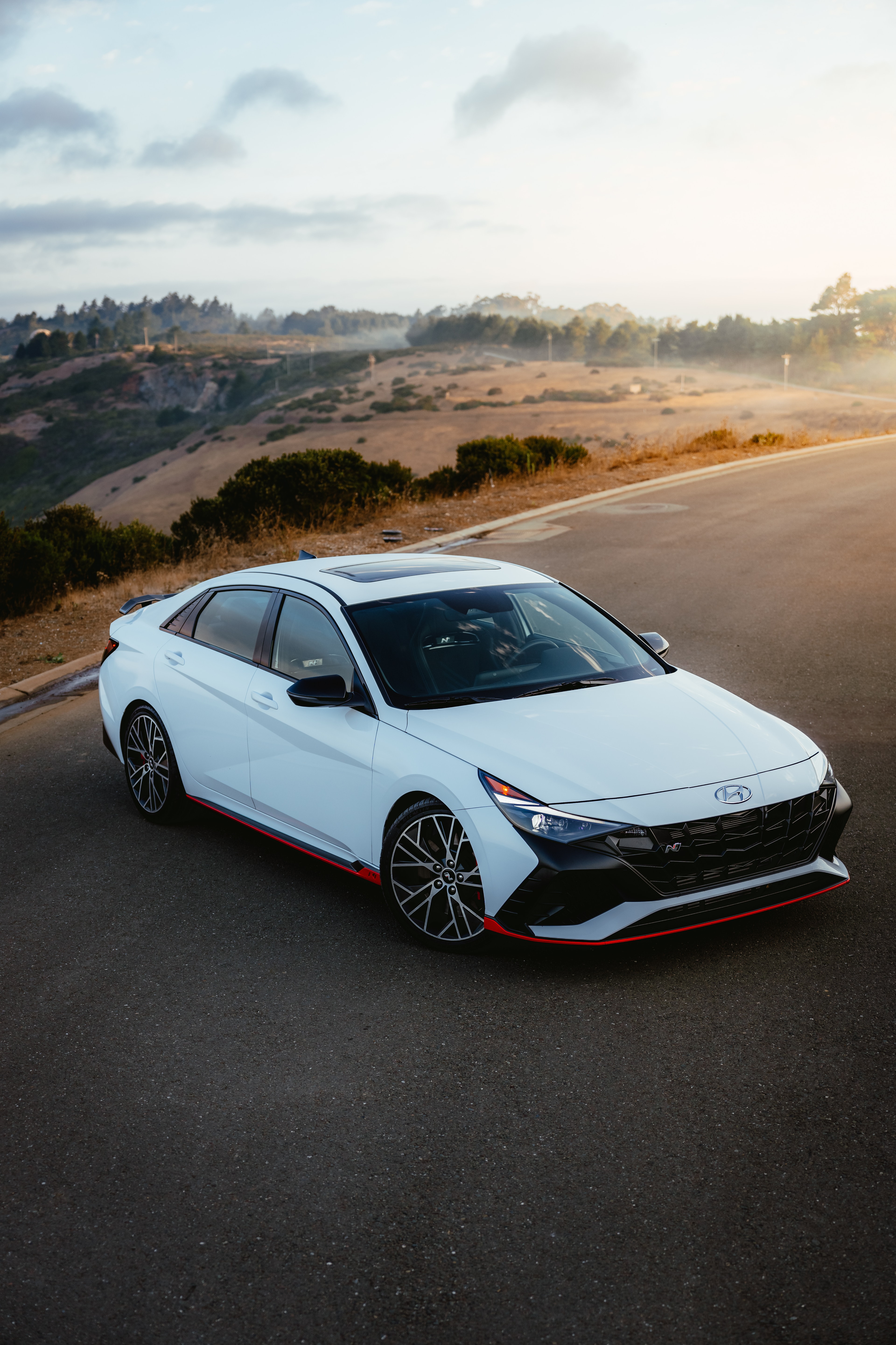 Hyundai Elantra N high-angle front three-quarter at the overlook, fog over the hills and ocean
