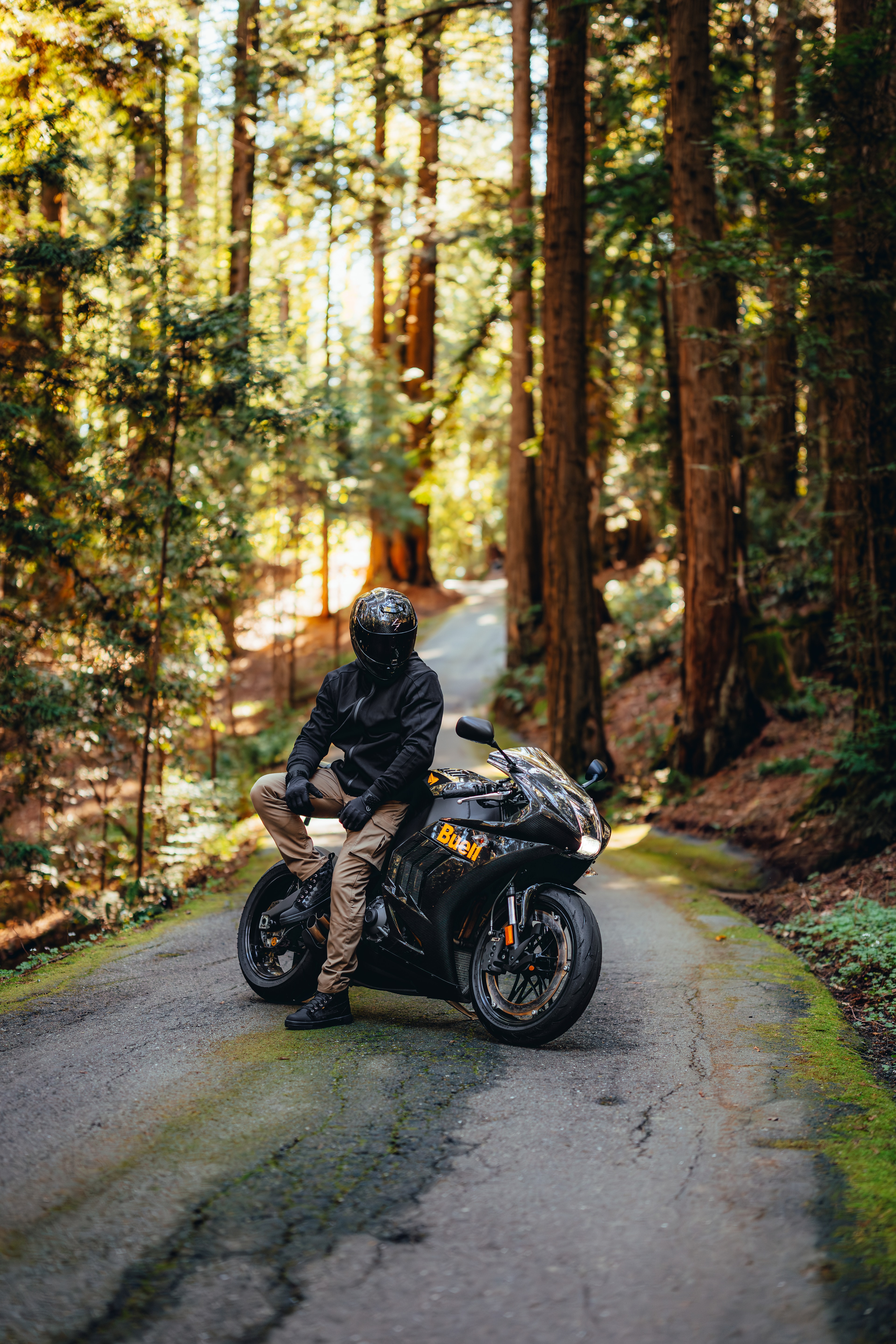 Rider sitting on the Buell among the redwoods, light through the trees