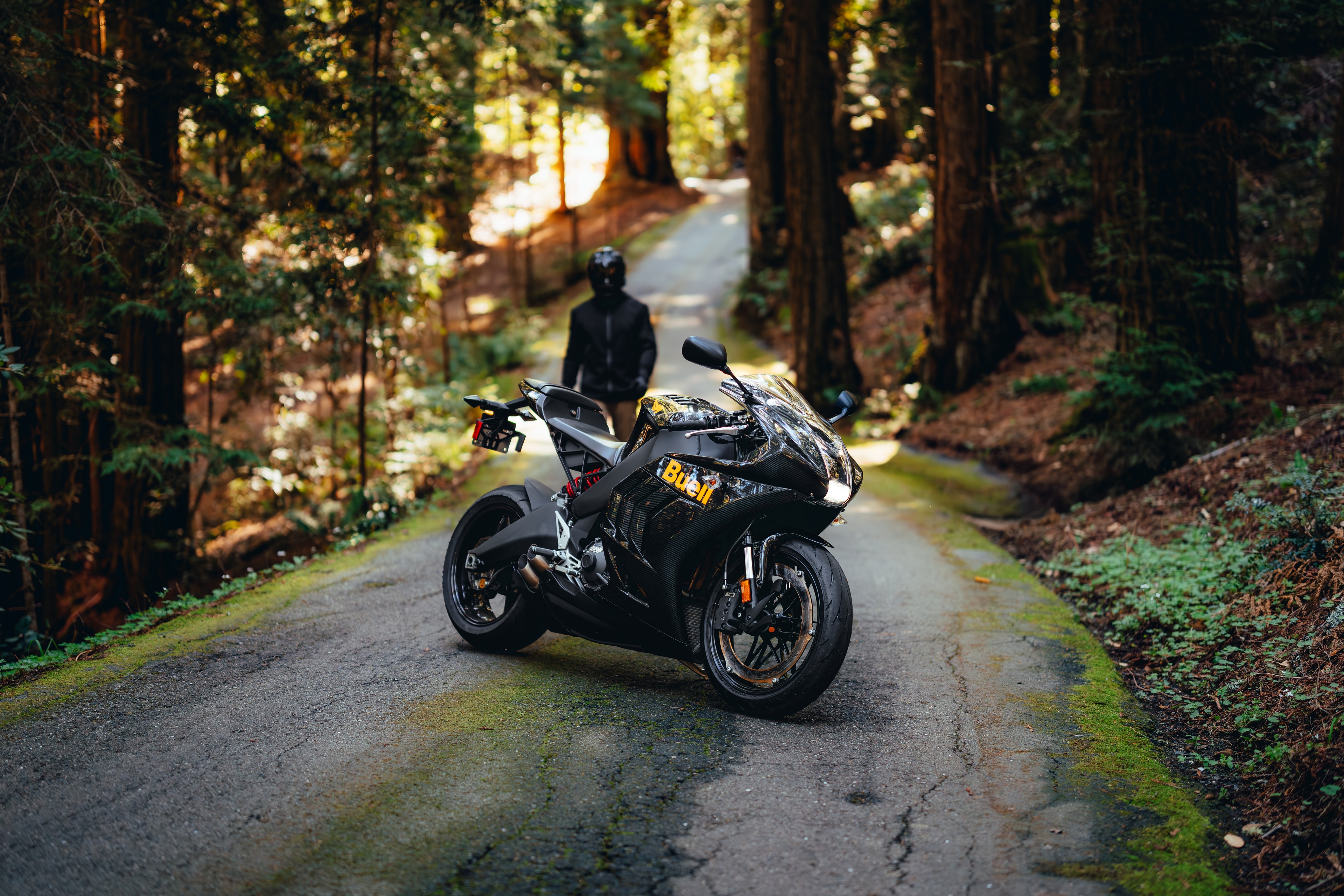 Faired Buell parked with the Buell tail branding, rider walking behind, redwood road