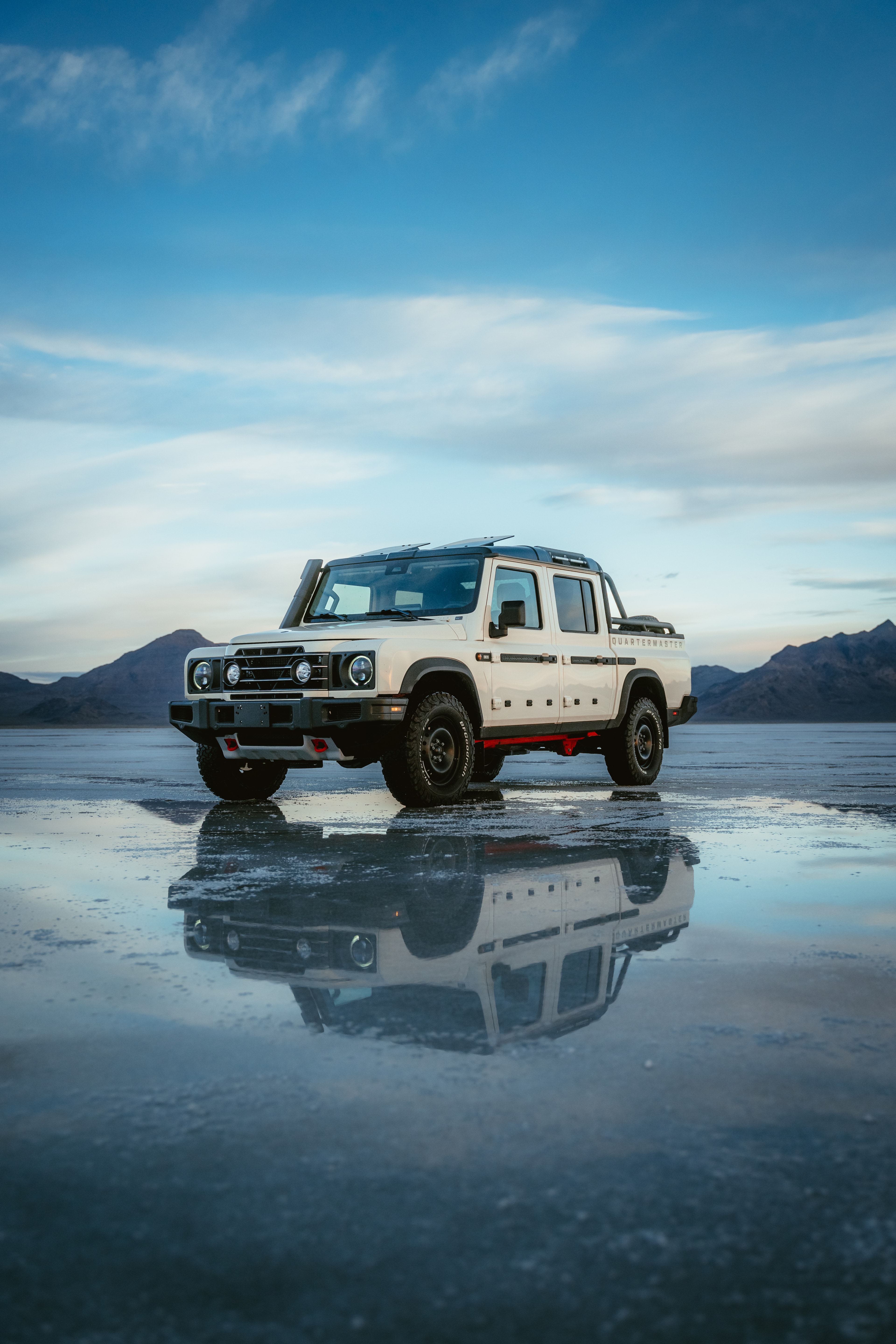 INEOS Grenadier Quartermaster at blue hour on the salt flats, distant mountains and a mirror reflection