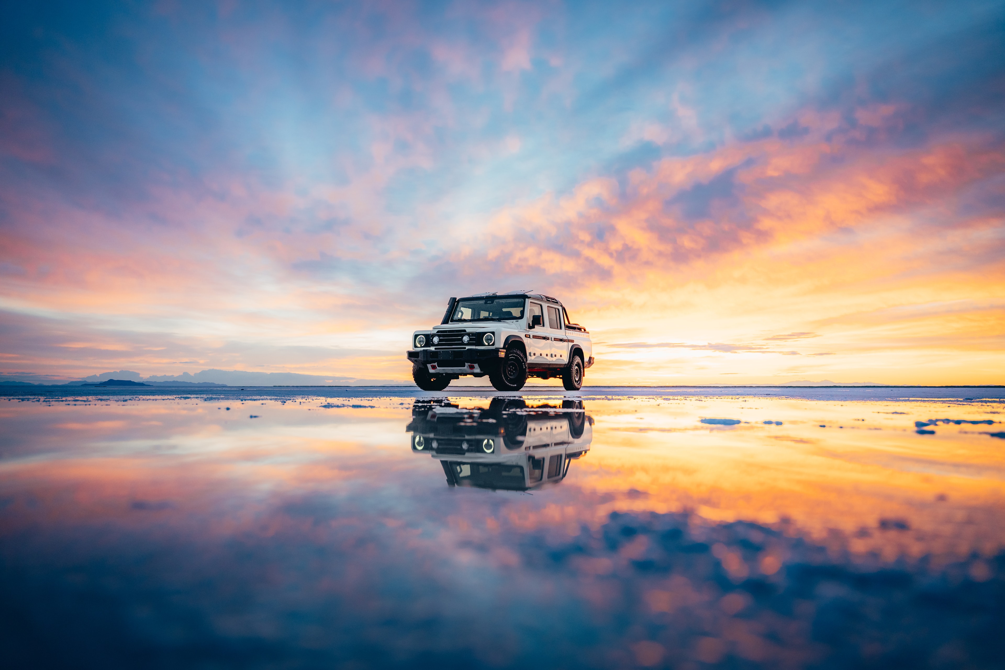 INEOS Grenadier Quartermaster mirrored in the wet salt flats at fiery sunset