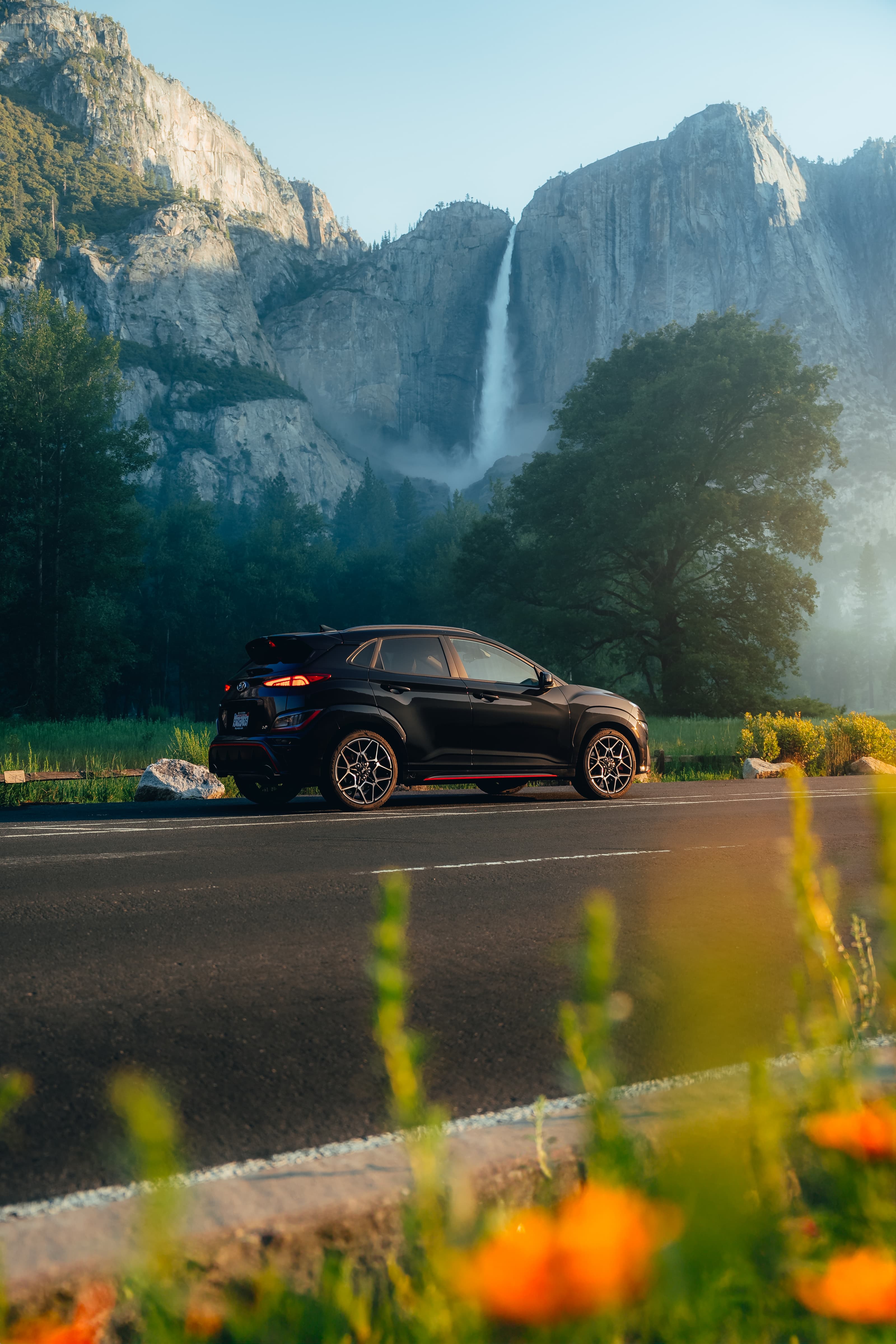 Black Hyundai crossover below Yosemite Falls, wildflowers in the foreground