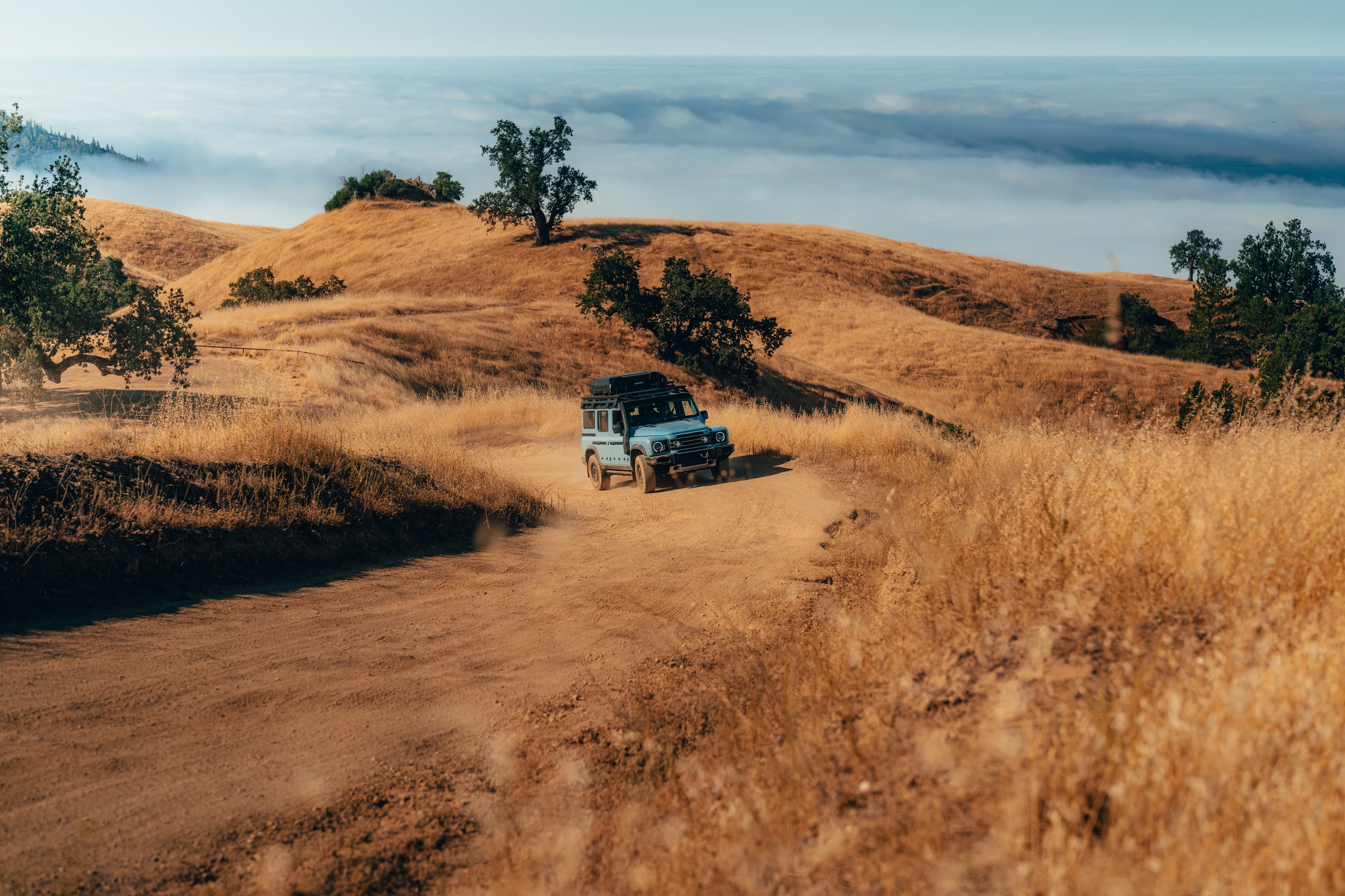 INEOS Grenadier on a dirt road through golden hills above the marine layer