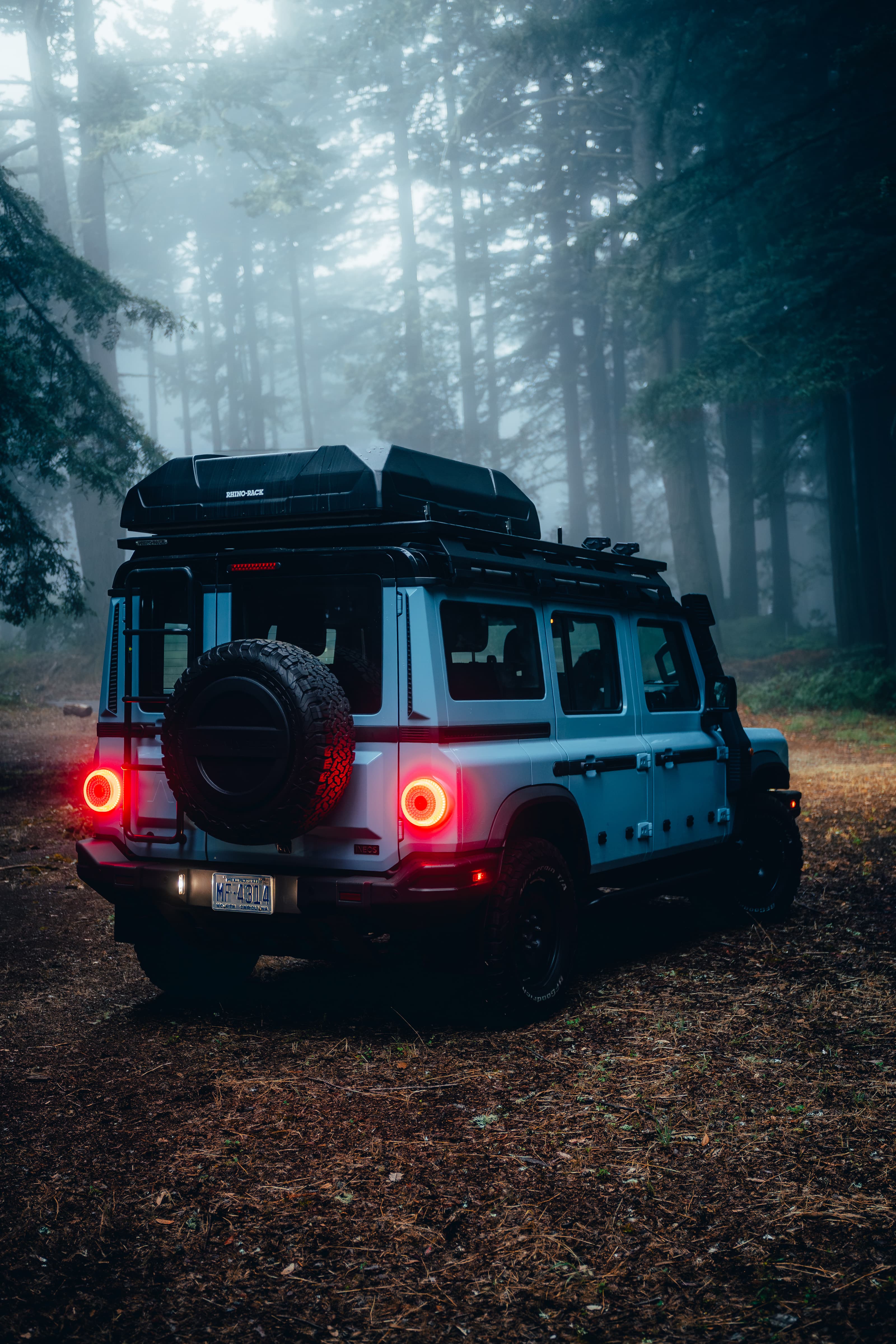 INEOS Grenadier rear in a foggy forest, tail lights glowing red