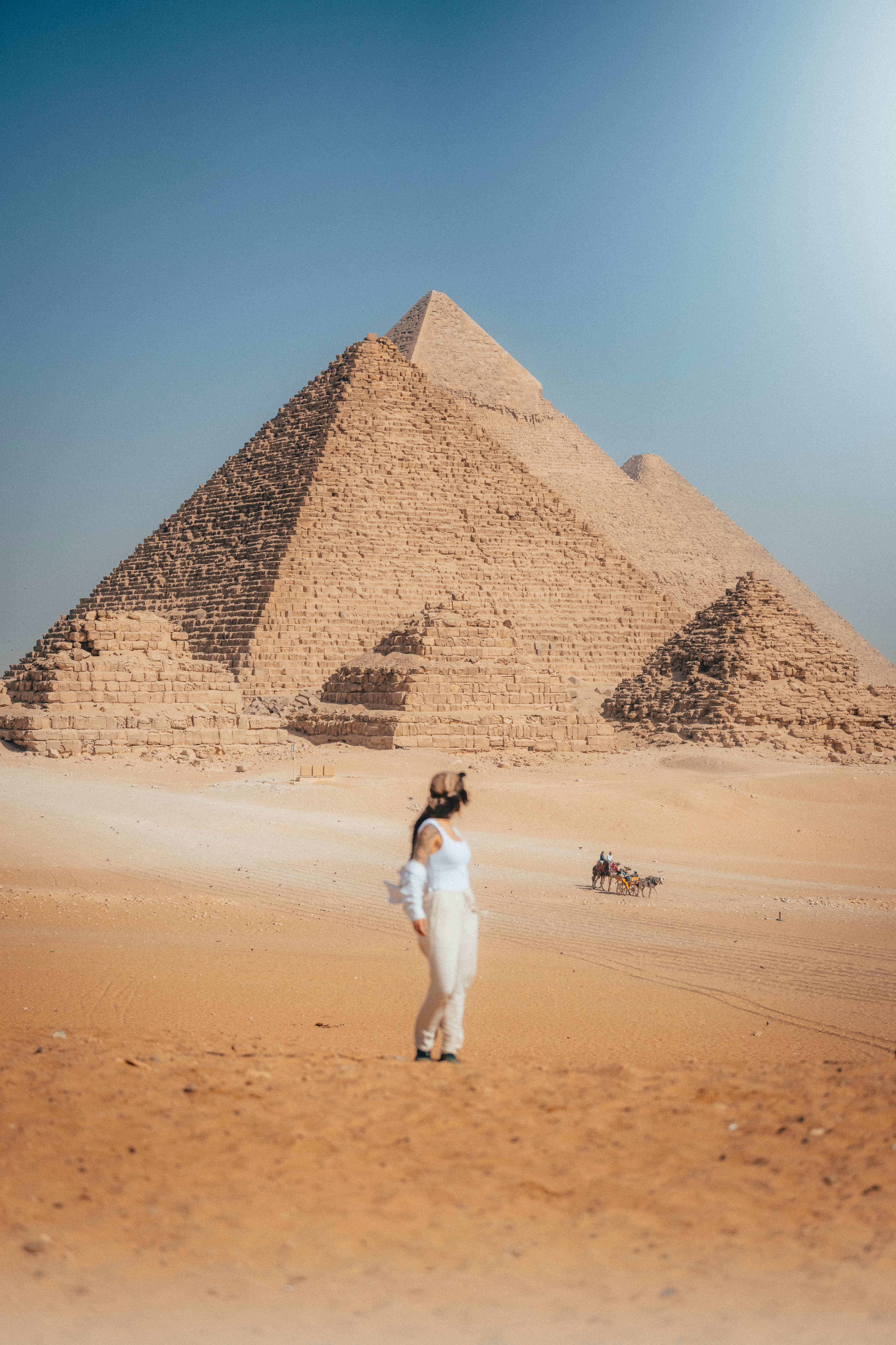 A lone figure in white standing on the sand before the Great Pyramid of Giza