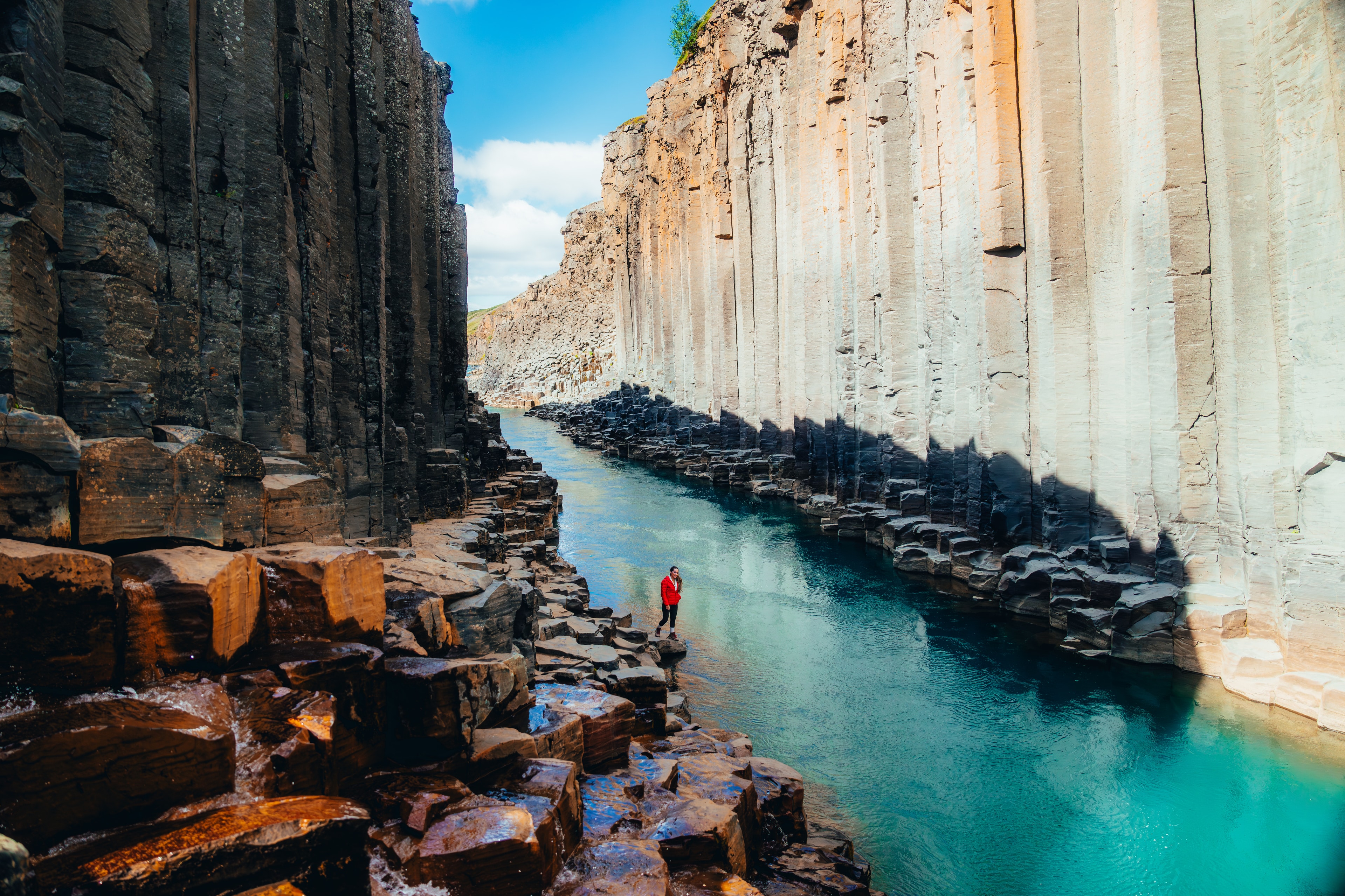 Studlagil basalt canyon opening wide above a glacial turquoise river