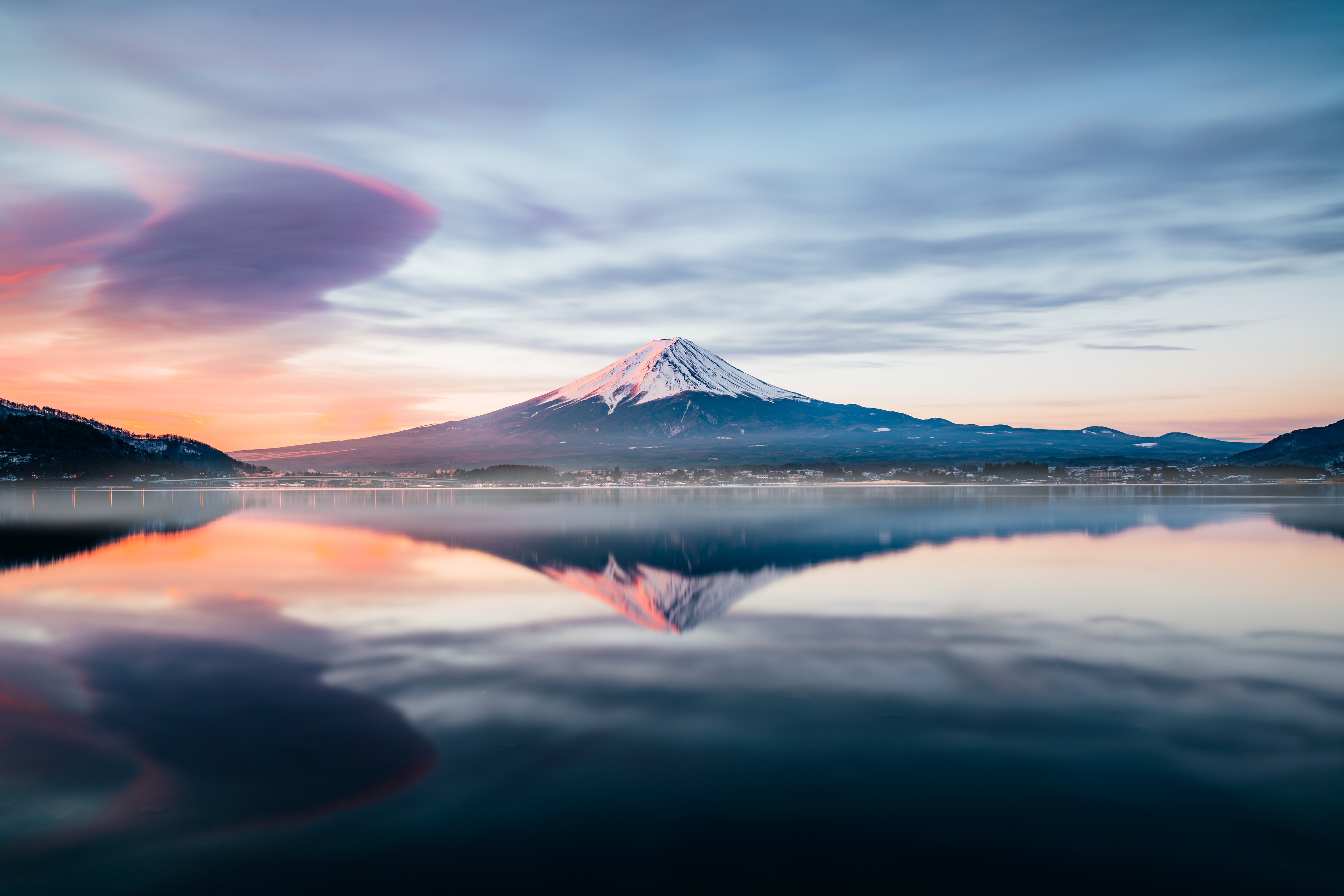 Mt Fuji under a long lenticular cloud at dawn, perfectly mirrored in the still lake below